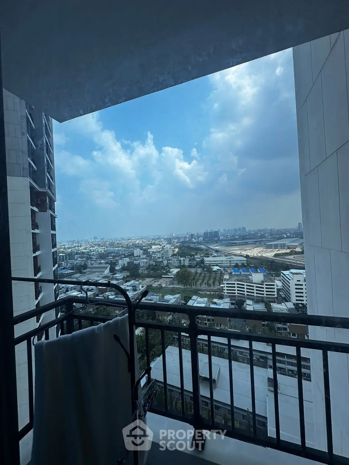 Stunning cityscape view from a high-rise balcony with clear skies and urban landscape.