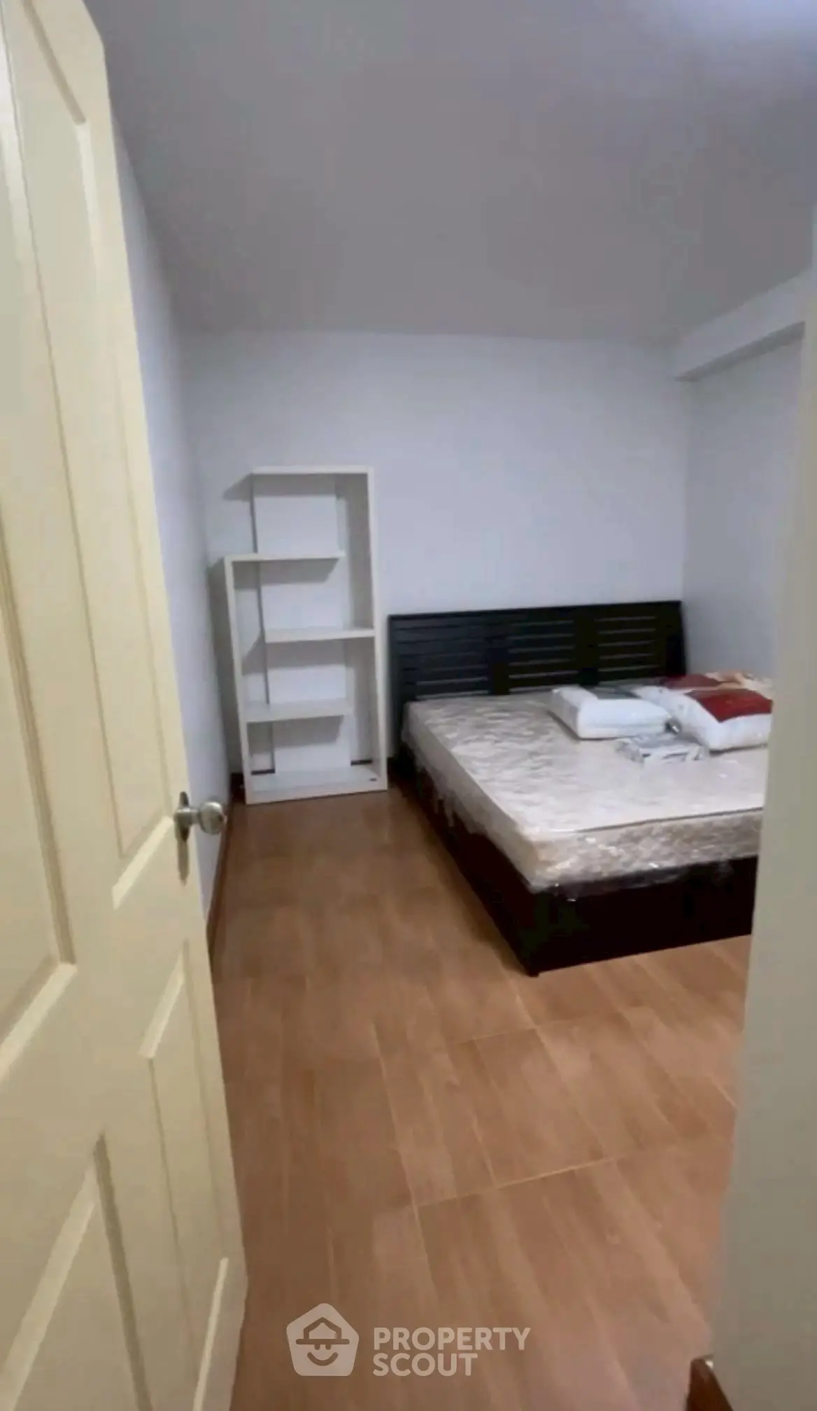 Cozy bedroom with wooden flooring and modern bed frame, perfect for relaxation.