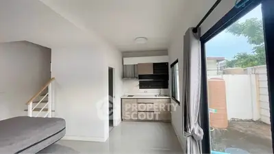 Modern open-plan living area with compact kitchen and large windows