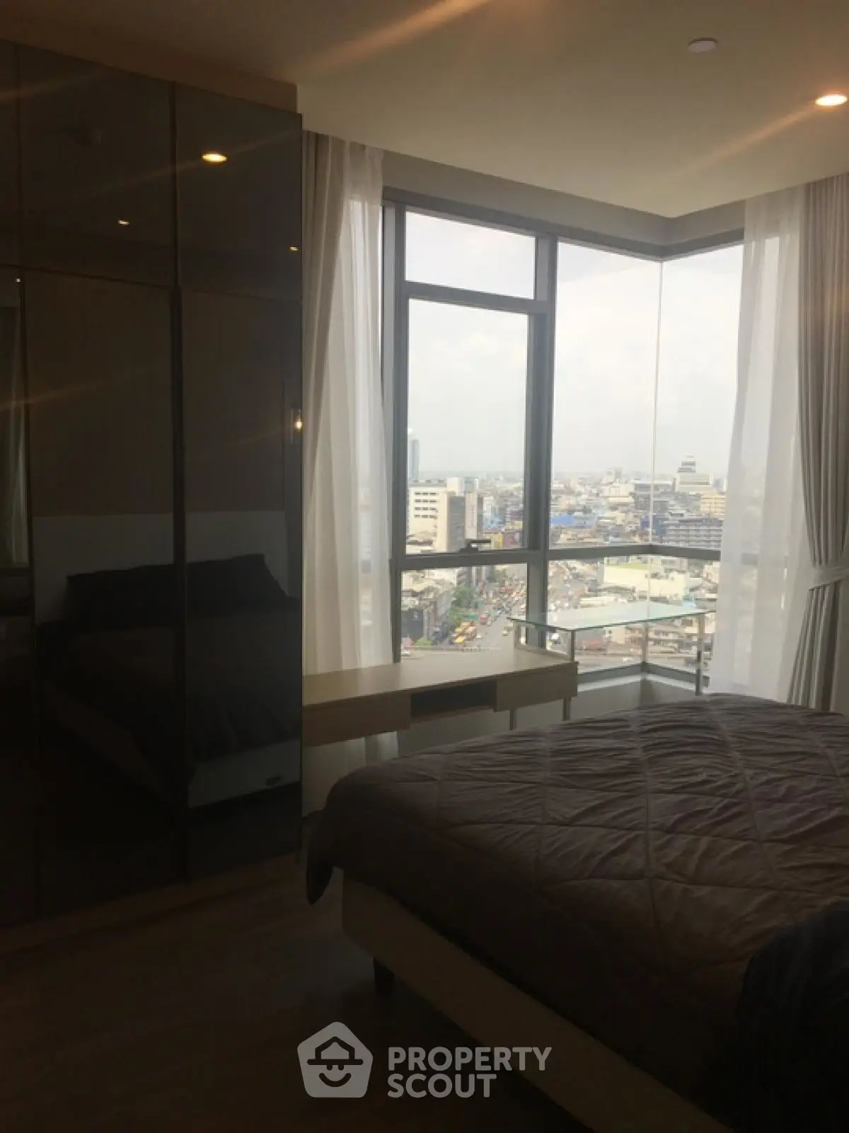 Modern bedroom with stunning city view from floor-to-ceiling windows.