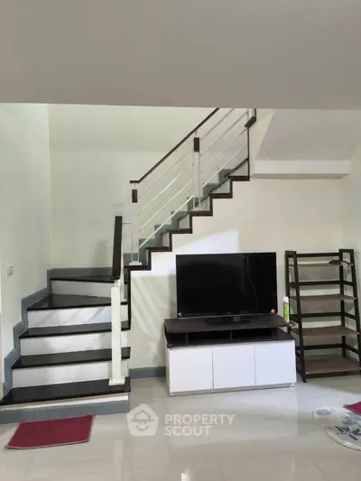 Modern living room with sleek staircase and TV unit, perfect for stylish urban living.