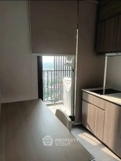 Modern kitchen with sleek cabinetry and balcony view in urban apartment