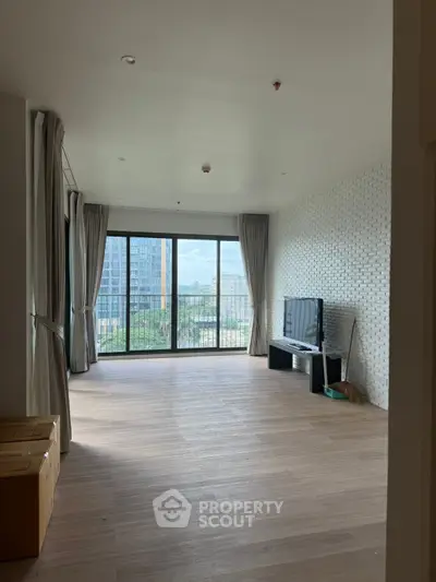 Spacious living room with large windows offering a stunning city view, perfect for modern urban living.