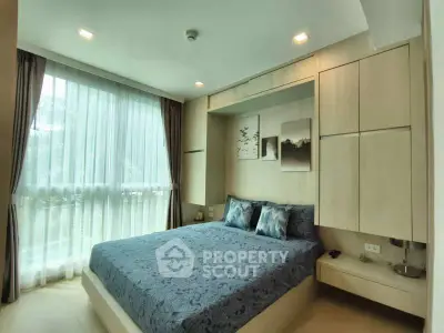 Modern bedroom with large window and stylish decor in a contemporary apartment.