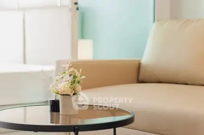 Elegant living room with beige sofa and stylish glass coffee table.