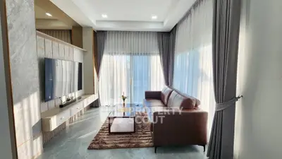 Modern living room with large TV, elegant curtains, and stylish furniture.