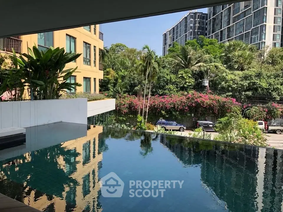 Luxurious infinity pool with lush greenery and modern buildings in the background, perfect for urban living.