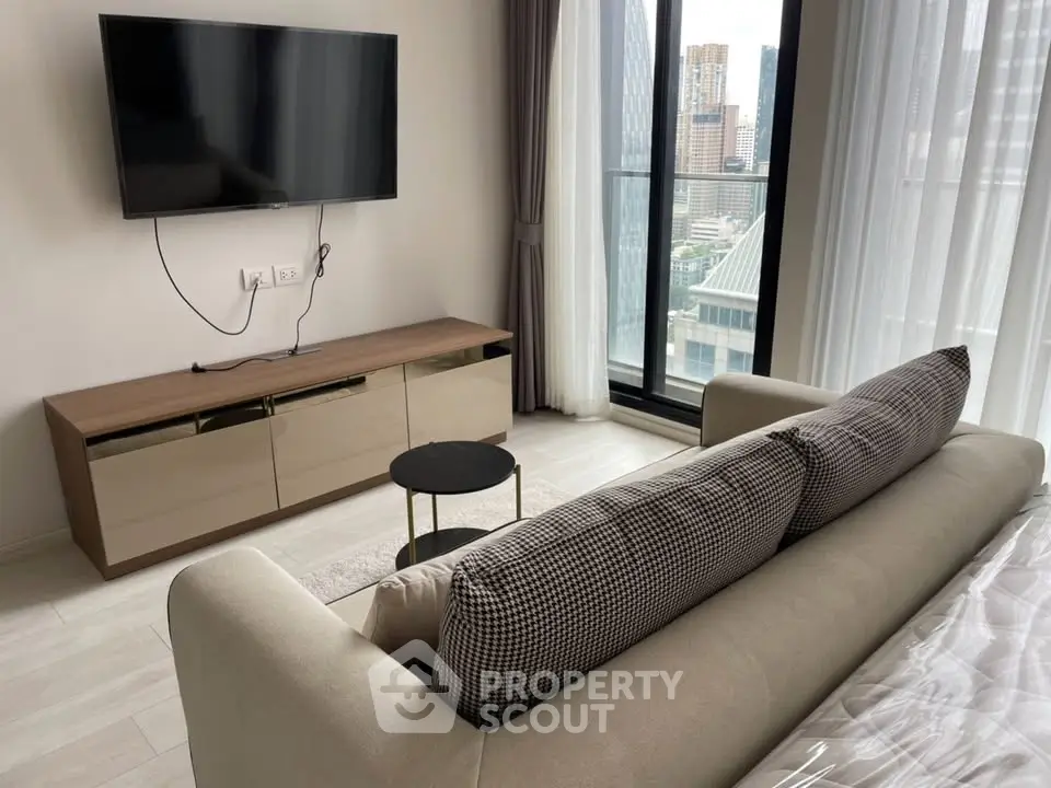 Modern living room with city view, featuring sleek TV setup and cozy sofa.