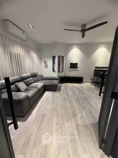 Modern living room with stylish decor, featuring a large sectional sofa and sleek flooring.