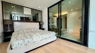 Modern bedroom with mirrored wall and sliding glass doors in luxury apartment
