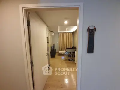 Modern apartment entrance leading to a cozy living room with wooden flooring and stylish decor.