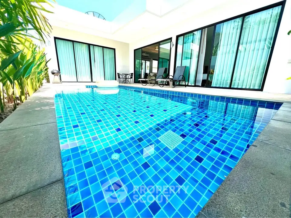 Luxurious private pool with modern villa and sunlit patio, perfect for relaxation and entertainment.
