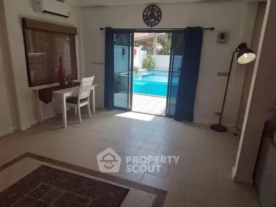 Spacious living room with pool view, featuring elegant decor and ample natural light.