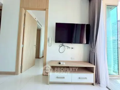 Modern living room with wall-mounted TV and natural light from large windows.