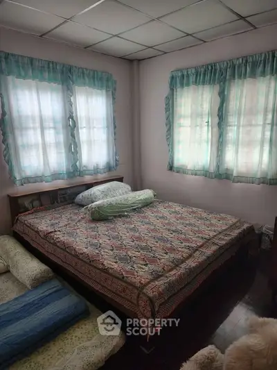 Cozy bedroom with large windows and patterned bedding, offering a warm and inviting atmosphere.