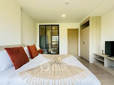 Modern bedroom with cozy decor and large glass doors leading to a balcony.