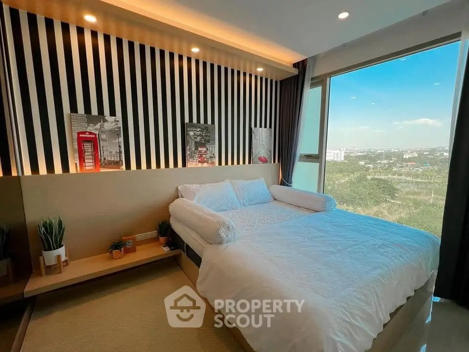 Modern bedroom with large window offering stunning city view and stylish decor.