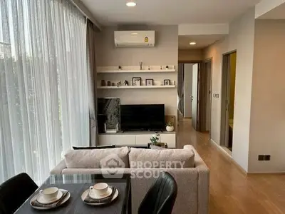 Modern living room with elegant decor and natural light, featuring a cozy dining area and stylish shelving.