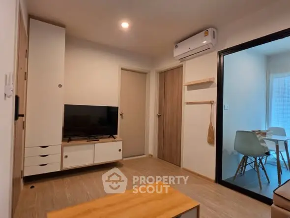Modern living room with TV and air conditioning, adjacent to dining area.