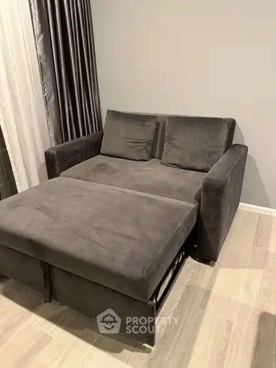 Modern living room with stylish gray sofa and matching ottoman on light wood flooring.