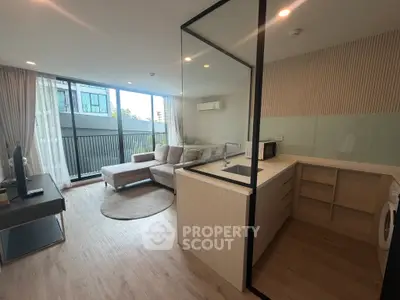 Modern open-layout living room with kitchen, featuring large windows and stylish furniture.