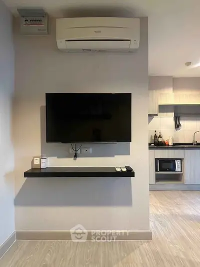 Modern living room with wall-mounted TV and sleek kitchen area