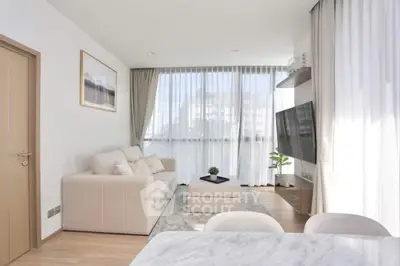 Bright modern living room with large windows, cozy sofa, and wall-mounted TV in stylish apartment.