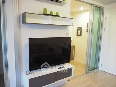Modern living room with sleek TV setup and sliding glass doors in stylish apartment.