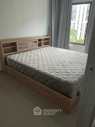 Spacious bedroom with modern bed and large window offering natural light.