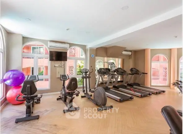 Spacious gym with modern equipment and large windows in luxury property.