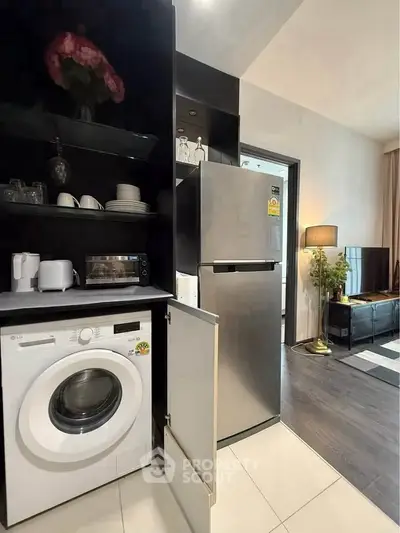 Modern kitchen with washing machine and stainless steel fridge in open layout apartment.