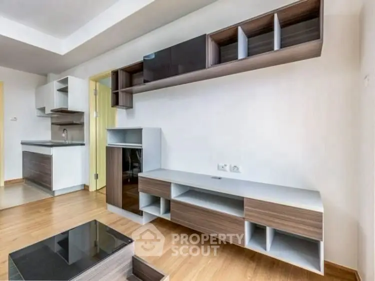 Modern living room with sleek wooden furniture and open kitchen layout.