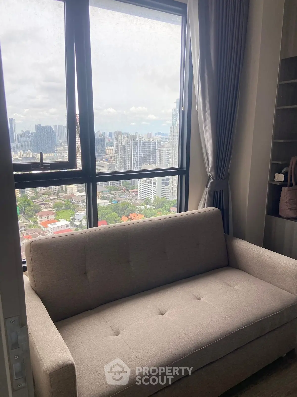 Cozy living room with a stunning city view from a high-rise apartment window.