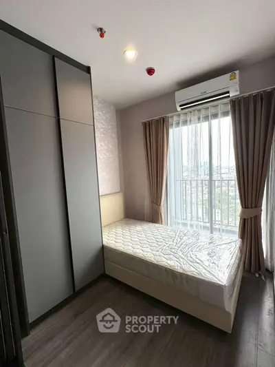 Cozy bedroom with large window and modern wardrobe, perfect for city living.