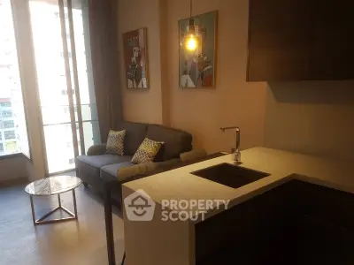 Modern living room with stylish decor and open kitchen layout, featuring a cozy sofa and elegant lighting.