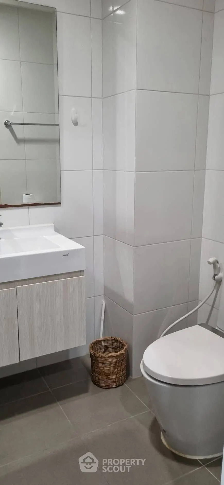 Modern bathroom with sleek fixtures and neutral tiles, featuring a stylish vanity and toilet.