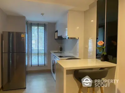 Modern kitchen with sleek design, featuring a breakfast bar and large window for natural light.