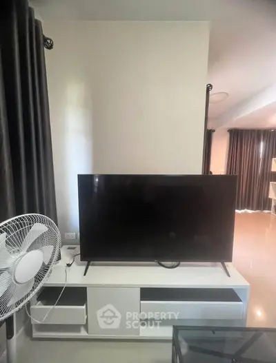 Modern living room with sleek TV stand and fan, perfect for cozy entertainment.