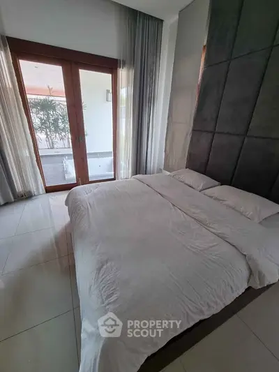 Spacious bedroom with large windows and modern decor, offering a serene and inviting atmosphere.