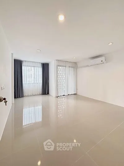 Spacious empty room with large windows and modern air conditioning unit.