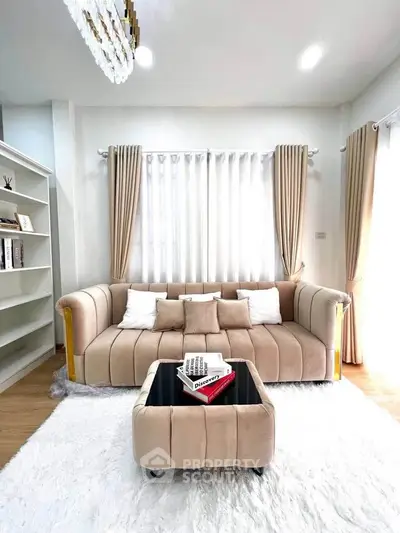Elegant living room with plush beige sofa, stylish ottoman, and chic decor in a bright, airy space.