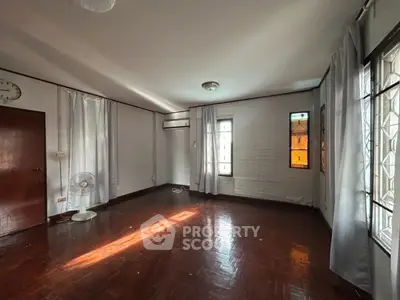 Spacious empty room with wooden flooring and natural light