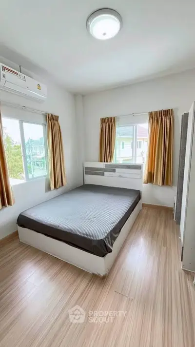Bright and airy bedroom with large windows and modern furnishings in a cozy apartment.