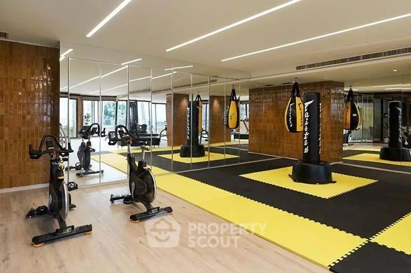 Modern gym with mirrored walls, exercise bikes, and punching bags in luxury real estate property.