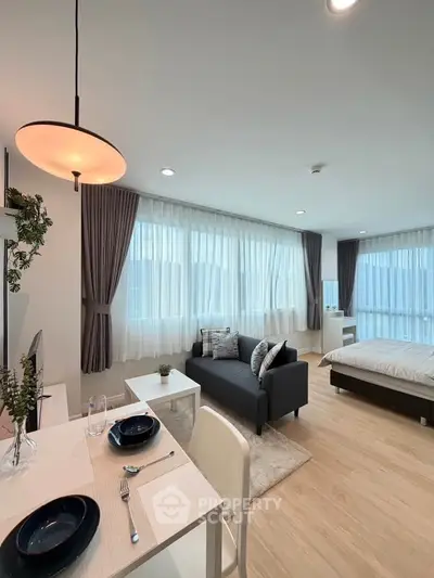 Modern studio apartment with open layout, featuring a cozy living area and elegant dining space.