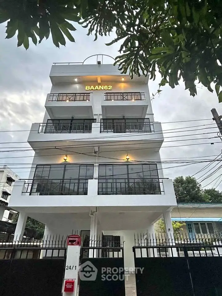Modern multi-story building with balconies and gated entrance in urban setting.