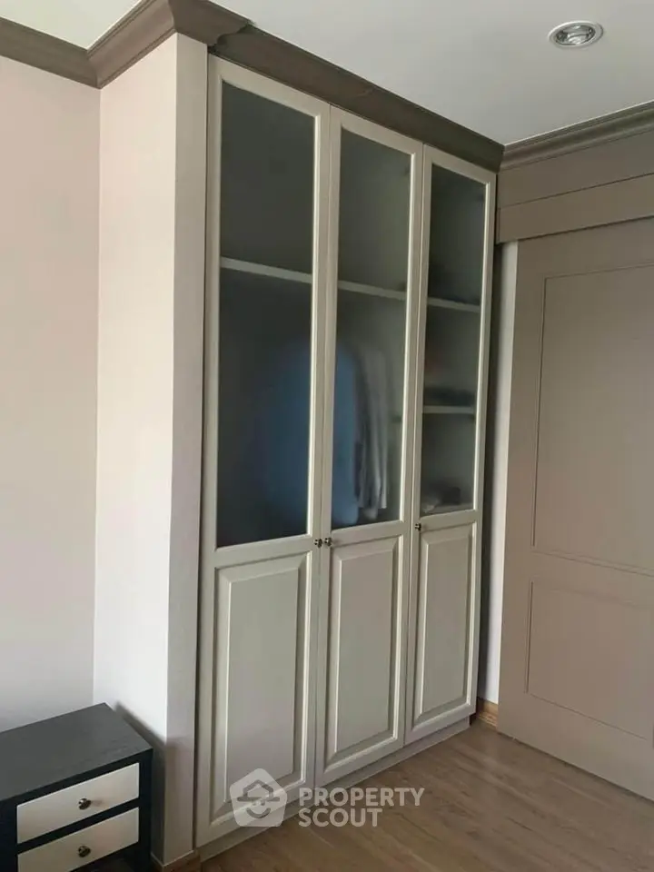 Elegant built-in wardrobe with frosted glass doors in a modern bedroom setting.