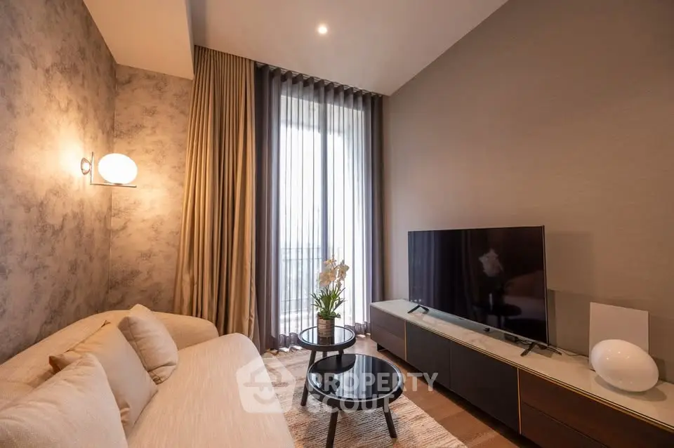 Modern living room with elegant decor and large TV, featuring stylish furniture and floor-to-ceiling curtains.
