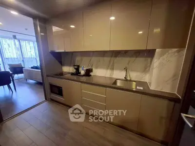 Modern kitchen with sleek cabinetry and open layout leading to a stylish living area.
