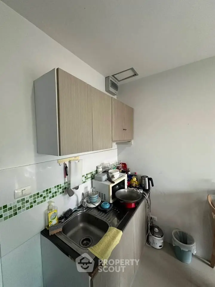 Compact kitchen with modern cabinets and appliances in cozy apartment